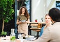 Waitress serving happy couple outdoors on terrace restaurant.