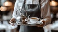 Waitress serving tea on a silver tray with a teapot and cup in a delightful setting Royalty Free Stock Photo