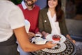 Waitress serving young beautiful couple in outdoor cafe Royalty Free Stock Photo