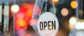 Waitress staff woman turning open sign board on glass door with bokeh light in cafe coffee shop Royalty Free Stock Photo