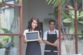 Waitress standing at the front of a cafe inviting people to come Royalty Free Stock Photo