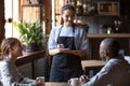 Waitress welcoming restaurant guests take order writing on notepad