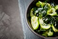 Wakame salad raw seaweed with cucumber slices and sesame in bowl on dark gray background close-up Royalty Free Stock Photo