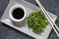 Wakame seaweed salad with sesame seeds and chili pepper in a bowl on black stone background. Top view Royalty Free Stock Photo