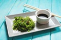 Wakame seaweed salad with sesame seeds and chili pepper in a bowl on blue wooden background Royalty Free Stock Photo