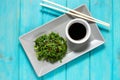 Wakame seaweed salad with sesame seeds and chili pepper in a bowl on blue wooden background. Top view Royalty Free Stock Photo