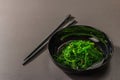 Wakame seaweed salad with sesame seeds and chili pepper in a bowl. Trendy hard light, dark shadow Royalty Free Stock Photo