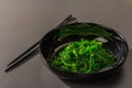 Wakame seaweed salad with sesame seeds and chili pepper in a bowl. Trendy hard light, dark shadow Royalty Free Stock Photo