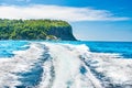 Wake of boat on water surface beside island coast Royalty Free Stock Photo