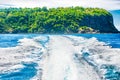 Wake of boat on water surface beside island coast Royalty Free Stock Photo