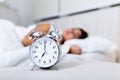 Wake up of an asleep girl stopping alarm clock on the bed in the morning. woman sleeping and wake up to turn off the alarm clock Royalty Free Stock Photo