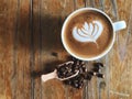 Wake up with love shape latte art coffee in the white cup and roasted coffee beans in spoon on the vintage wooden Royalty Free Stock Photo