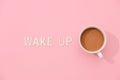 WAKE UP text with a cup of coffee with shadow on pink background Royalty Free Stock Photo