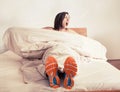 Wake up yawning girl in run shoes sitting in bed Royalty Free Stock Photo