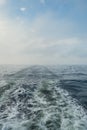 Wake of vessel. Wide wake trail from boat. Ocean water. Deep blue. Trace from large ship. Sunset rays on water from Royalty Free Stock Photo