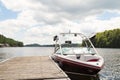 A wakeboard boat at a wooden dock in the Muskokas on a sunny day. Royalty Free Stock Photo