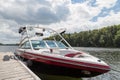 A wakeboard boat at a wooden dock in the Muskokas on a sunny day.