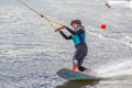 Wakeboarder girl surfing across a lake in spring in Sweden