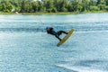 Wakeboarder jumps from a springboard behind a rope and makes a wave on the water Royalty Free Stock Photo
