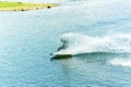 Wakeboarder jumps from a springboard behind a rope and makes a wave on the water Royalty Free Stock Photo