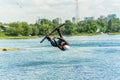 Wakeboarder jumps from a springboard behind a rope and makes a wave on the water Royalty Free Stock Photo