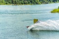 Wakeboarder jumps from a springboard behind a rope and makes a wave on the water Royalty Free Stock Photo