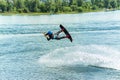 Wakeboarder jumps from a springboard behind a rope and makes a wave on the water Royalty Free Stock Photo