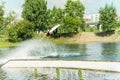 Wakeboarder jumps from a springboard behind a rope and makes a wave on the water Royalty Free Stock Photo