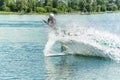 Wakeboarder jumps from a springboard behind a rope and makes a wave on the water Royalty Free Stock Photo