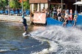 An athlete wakeboarder dynamically makes a U-turn on a water board in front of the stands of spectators on a summer day. 06.19.