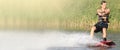 Wakeboarder trains in the lake at sunny day. Space for text. Panoramic view Royalty Free Stock Photo