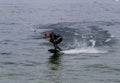 Wakeboarding with a guide mechanism. An unknown athlete holds on to the cable, performing tricks in the direction of travel