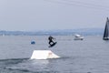 Wakeboarding with a guide mechanism. An unknown athlete holds on to the cable, performing tricks on the water trampoline