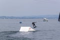 Wakeboarding with a guide mechanism. An unknown athlete holds on to the cable, performing tricks on the water trampoline