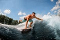 Wakesurfer rides along the wave and touches the spray of water with his hand