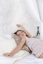 Waking up cute girl sleeping on a special beauty pillow with a silk pillowcase. Vertical photo Royalty Free Stock Photo