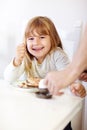 Waking up to a nutritious breakfast. A little girl smiling at the camera while eating breakfast. Royalty Free Stock Photo