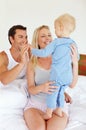 Waking up to our favourite smile. Two parents playing lovingly with their young son on their bed. Royalty Free Stock Photo