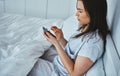 Waking up to a text message. High angle shot of an attractive young woman reading her text messages while lying in bed. Royalty Free Stock Photo