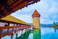 Walk along covered wooden Kapellbrucke Chapel Bridge in Lucerne, Switzerland