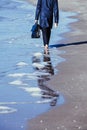 Walk bare foot beach sea man feet trousers raincoat feet briefcase bag blue water sky reflection Royalty Free Stock Photo