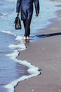 Walk bare foot beach sea man feet trousers raincoat feet briefcase bag blue water sky reflection Royalty Free Stock Photo