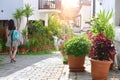 Walk through the beautiful Mediterranean streets. Flowerpots with flowers are on the ground. Tourist girl with backpack goes down.