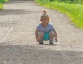 On the walk, the child sits on the road.