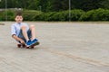 On a walk in the park a boy sits on a skateboard and rides