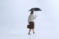 Portrait of senior sad woman in retro style, fashion of 70s, 60s years walking with umbrella isolated on white studio Royalty Free Stock Photo