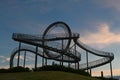 Walkable Tiger and Turtle roller coaster sculpture on Magic Mountain against a dark blue sky with rose clouds, art installation