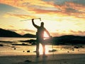 Walker watch sunny spring daybreak over sea. Hiker with backpack stand on sandy shore. Sun rays Royalty Free Stock Photo