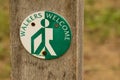 Walkers Welcome round sign in green and white on post welcoming visitors to cafe.