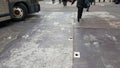 Walking accross the urban street with bus turning and metal street hihole covers